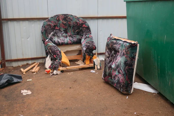 찢어진 장식이 오래된 안락의자가 쓰레기통에 던져졌습니다 — 스톡 사진