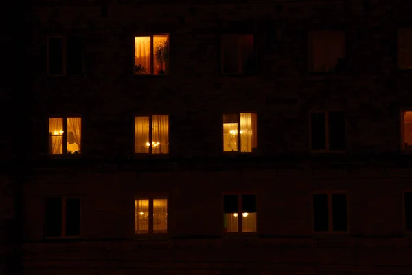Illuminated in the dark of the night the windows of the houses of an apartment house