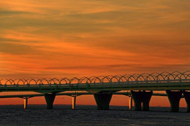 deniz üzerinde geçen bir otoban üzerinde batan güneşin ışınları akşam gökyüzü