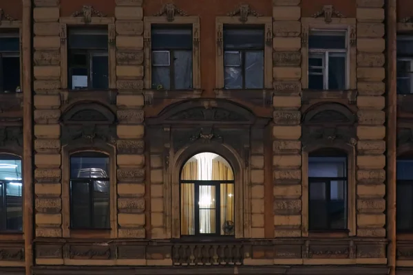 light in the window of an old building with a fan on the windowsill