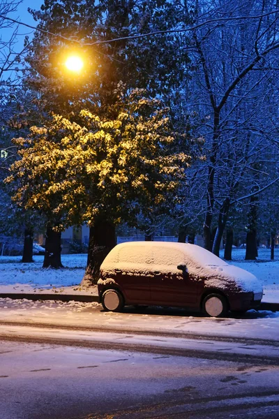 a car parked under the lantern spotted by the first snow