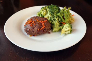 Biftek, havuçlu, brokolili ve kafede bir tabakta.