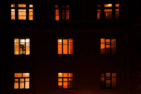 Gecenin karanlığında elektrik ışığıyla aydınlatılan bir apartmanın dokuz penceresi.