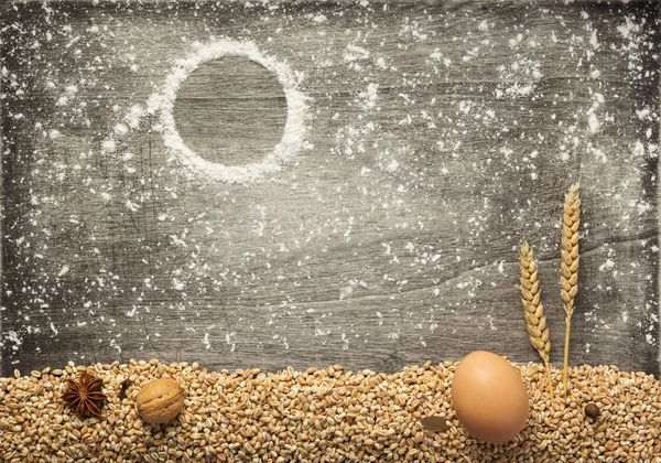 wheat grains and bakery ingredients on wooden background, top view