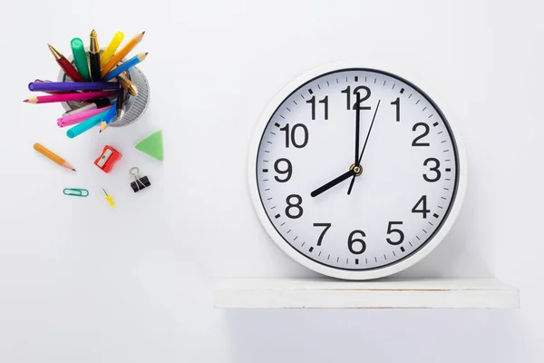 Wall clock at wooden shelf and school accessories — Stock Photo, Image