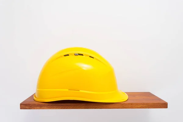 Construction helmet on wooden shelf at white — Stock Photo, Image