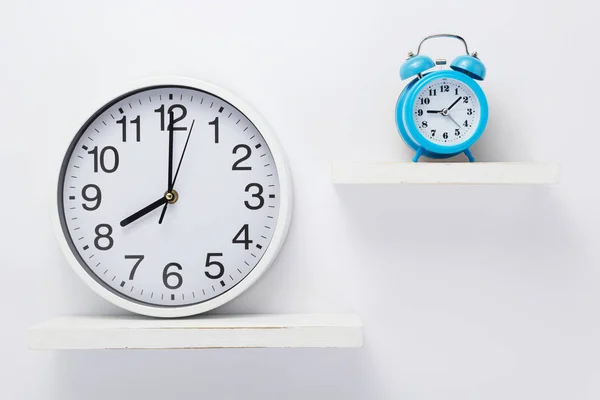 Wall clock at wooden shelf on white — Stock Photo, Image
