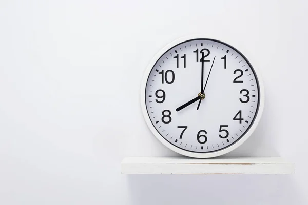 Wall clock at wooden shelf on white — Stock Photo, Image