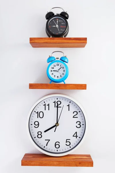 Despertador y reloj de pared en estante de madera — Foto de Stock