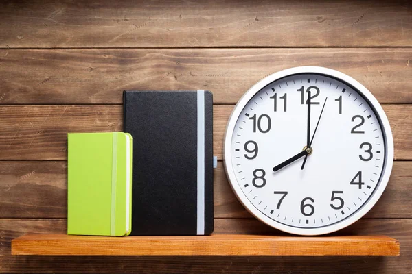 Reloj de pared y libro en estante sobre fondo de madera —  Fotos de Stock