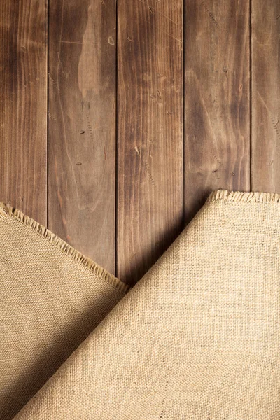 Arpillera hessiana saqueo sobre tabla de fondo de madera —  Fotos de Stock