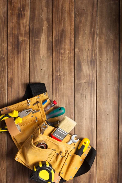 Instruments in tool belt at wooden table — Stock Photo, Image