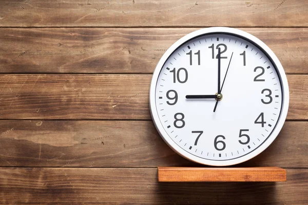 Reloj de pared en estante sobre fondo de madera —  Fotos de Stock