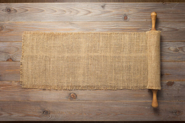 rolling pin and sacking burlap at wooden board