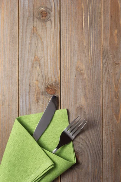 Cuchillo y tenedor en servilleta sobre fondo rústico de madera — Foto de Stock