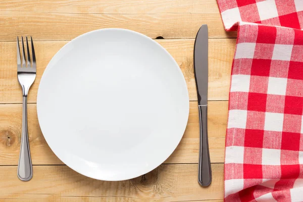 Tallrik, kniv och gaffel på trä bordsbakgrund — Stockfoto