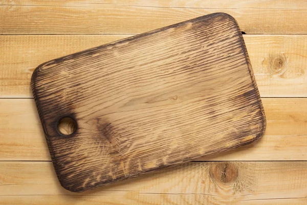 Cutting board at rustic wooden plank — Stock Photo, Image