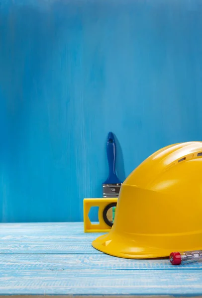 Construction helmet and tools on wooden table — Stock Photo, Image