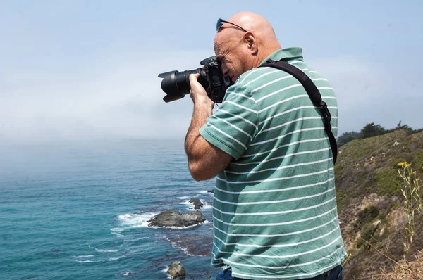Male Photographer taking pictures at the cliff Stock Picture