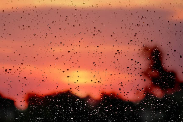 日出时 天空和树木模糊背景上的玻璃上的水滴 — 图库照片