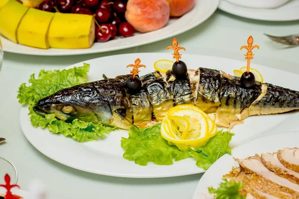 他の料理と一緒に お祝いのテーブルの上に緑とレモンと詰め魚 — ストック写真