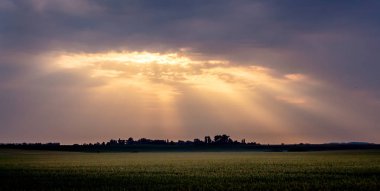 Karanlık gökyüzü bulutlu gündoğumu sırasında. Güneş ışınlarının bir kara bulut break