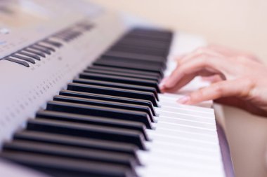 Genç bir kızın yanında piyano tuşları elleri. Kız piyano çalıyor. Bir müzik parçası bir piyanoda gerçekleştirme