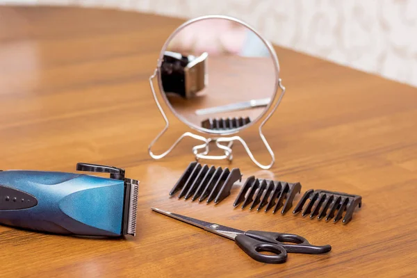 A table in the hairdressing salon with tools for haircuts: trimmer with nozzles, scissors, mirror