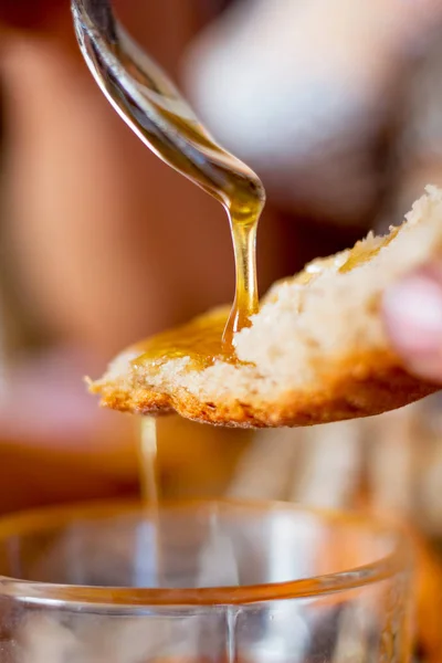 Honey   flows from a spoon to bread. Honey - a good food with medicinal properties