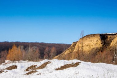 Bir güneşli kış gününde orman yakınlarındaki kayalık tepe