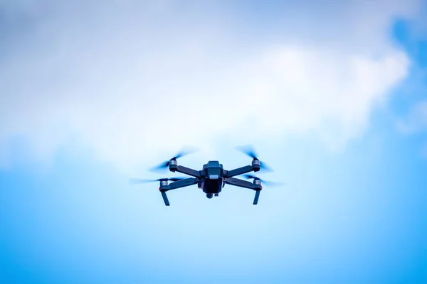 Quadcopter on the background of a blue sky while shooting a photo and video