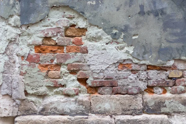 Hasarlı alçı duvar eski bir bina. Hasarlı sıva ile tuğla görebilirsiniz