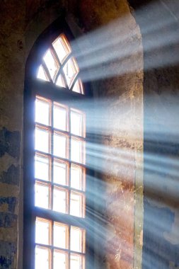 The bright ray of the sun penetrates through the window of the old church clipart