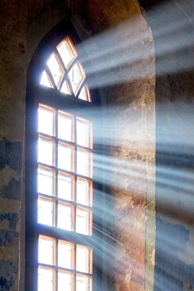 The bright ray of the sun penetrates through the window of the old church