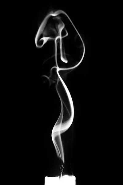 Smoke from a candle on a black isolated background. An interesting and weird smoke pattern