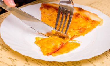 Bir kız çatal ve bıçak kullanarak yemek yiyor.