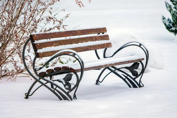 Snow-covered bench in the city park. Winter in the city