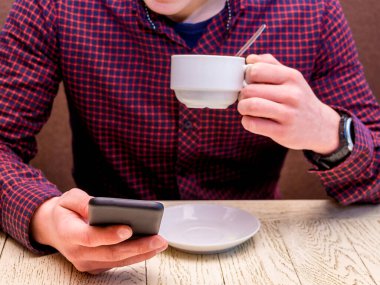 Ofiste bir iş adamı cep telefonu ve bir fincan kahveyle.