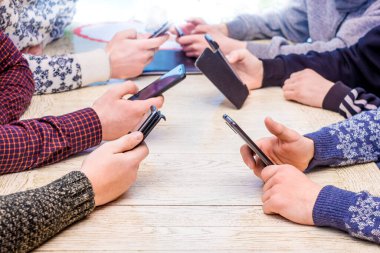 Ofisteki adamlar akıllı telefonları ellerinde tutuyorlar. Gençler akıllı telefonlarla eğlenir. Cep telefonlarında oyunlar