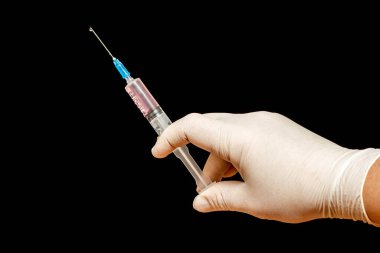 Doktorun elindeki şırınga siyah izole arka planda.