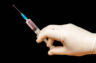 Doktorun elindeki şırınga siyah izole arka planda.