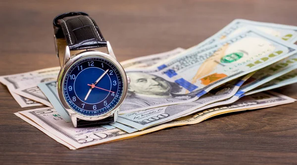 The watch is lying on dollars. Time to earn money. Time is money