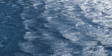 Arka plan, güneşin yansıttığı karanlık dalgaların dokusu. Rüzgarlı havada, nehrin yüzeyinde kara dalgalar var.