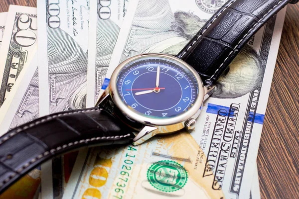 The watch is lying on dollars. Time to earn money. Time is money