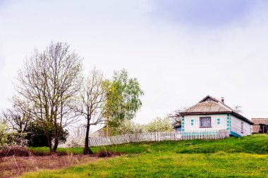 Dağlarda, yeşilliklerin ve çiçeklerin arasında eski bir kır evi.