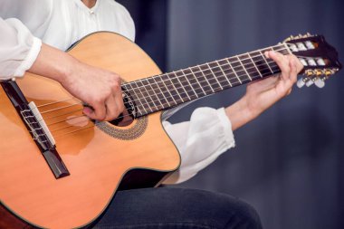 Beyaz gömlekli bir kız gitar çalıyor. Gitaristin konserinde performans