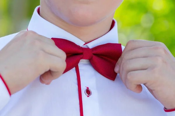 A young man corrects a red bow tie