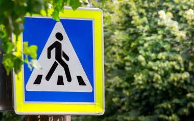 İşaret yeşil ağaçların arka planında yaya geçidi.