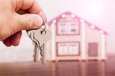 Yeni bir evin arka planında anahtarlar bir adamın elinde. Satış ve ev satın alma