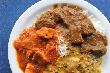 Üç Hint köriler (Rogen Josh, Madras, Tikka Masala) üzerinde bir tabakta görünümünü yukarıda. Hint yemekleri arka planlar ve mutfağı dokular. Kopya alanı